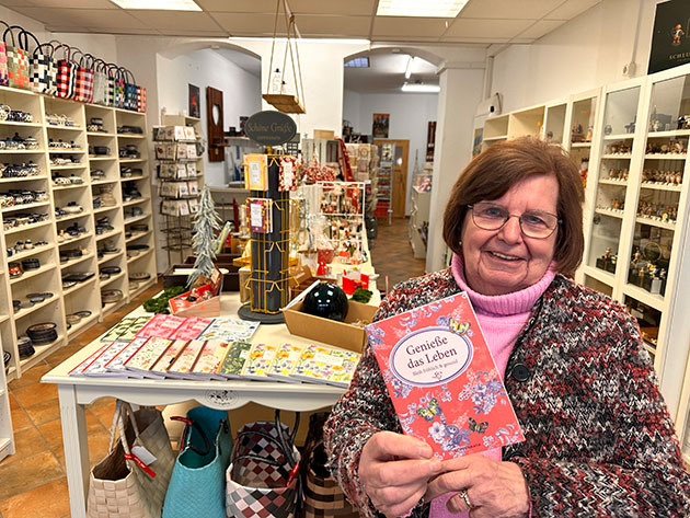 Frau im Laden mit einer Karte: Genieße das Leben.