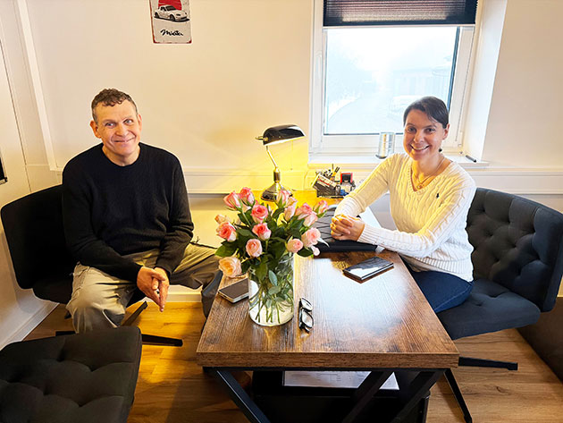 Zwei Leute am Tisch mit Blumen und Lächeln.