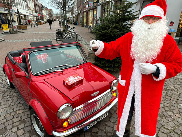 Weihnachtsmann mit rotem Auto voller Geschenke
