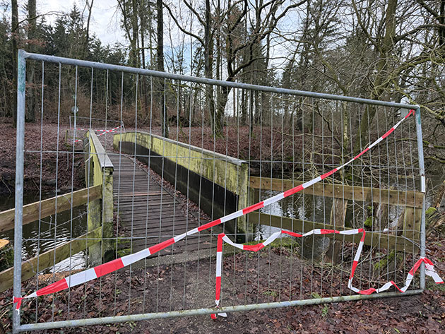 Absperrung vor einer gesperrten Brücke im Wald.