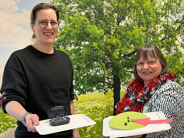 Zwei Frauen halten Tabletts mit Objekten in der Natur.