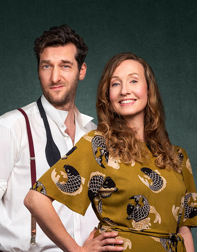 Ein Mann und eine Frau lächeln vor grünem Hintergrund.