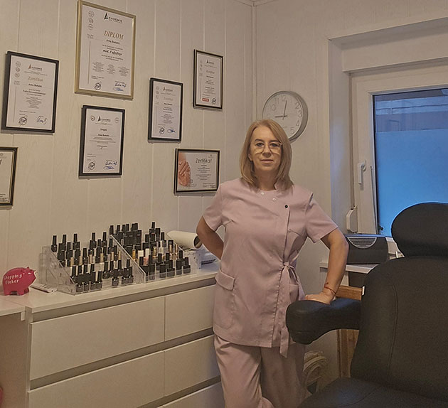 Frau in rosa Arbeitskleidung in einem zertifizierten Nagelstudio.