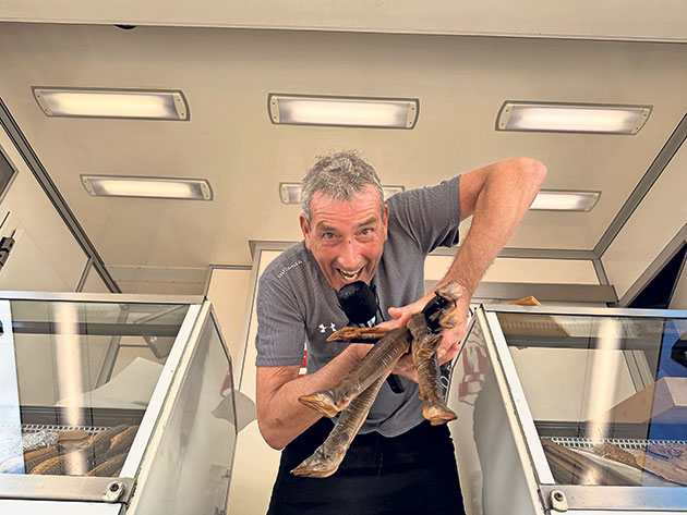 Mann posiert mit Fischvorführungszange