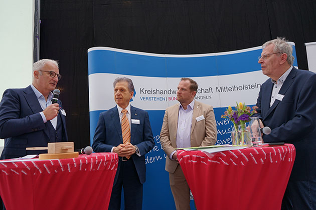 Vier Männer bei einem Podiumsgespräch mit Mikrofonen.