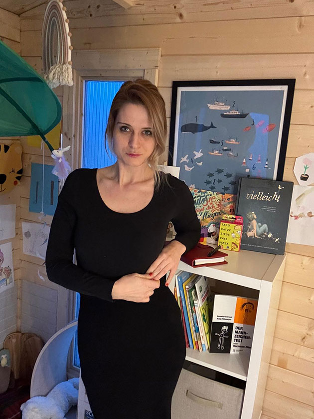 Person in einem Zimmer mit Büchern und Bildern an der Wand.