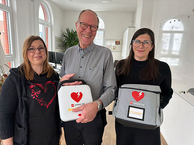 Drei Personen halten Herzsymboltaschen im Büro.