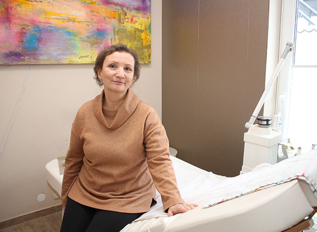 Frau sitzt auf einem Stuhl in einem bunten Raum.