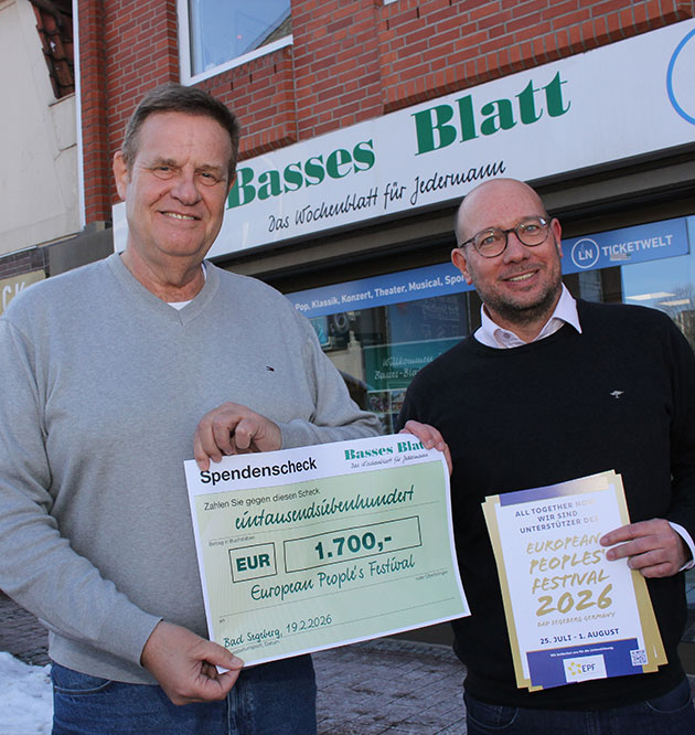 Zwei Männer halten einen Scheck vor einem Bürogebäude.