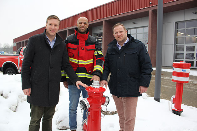 Drei Männer stehen neben einem Hydranten im Schnee.