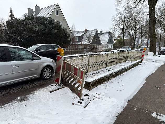 Baustelle auf verschneiter Straße mit parkenden Autos