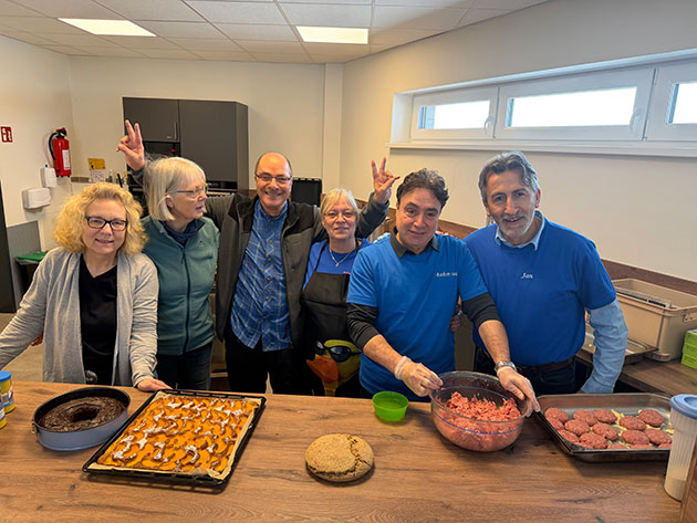 Sechs Personen in Küche mit Kuchen und Fleischbällchen.
