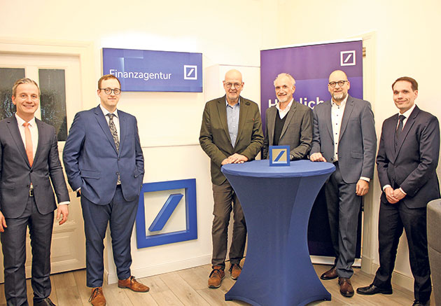 Sechs Männer in Anzügen vor einem Finanzagentur-Schild.