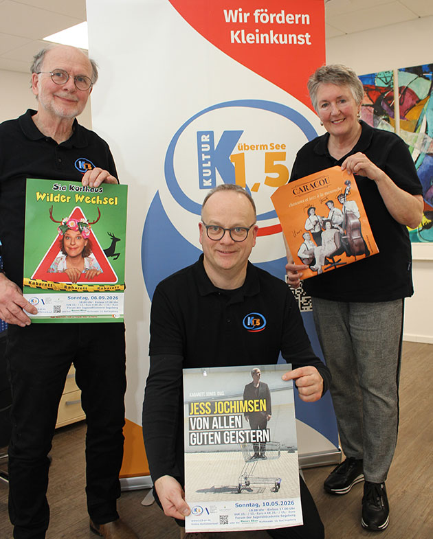 Drei Personen halten Werbeplakate vor einem Banner.