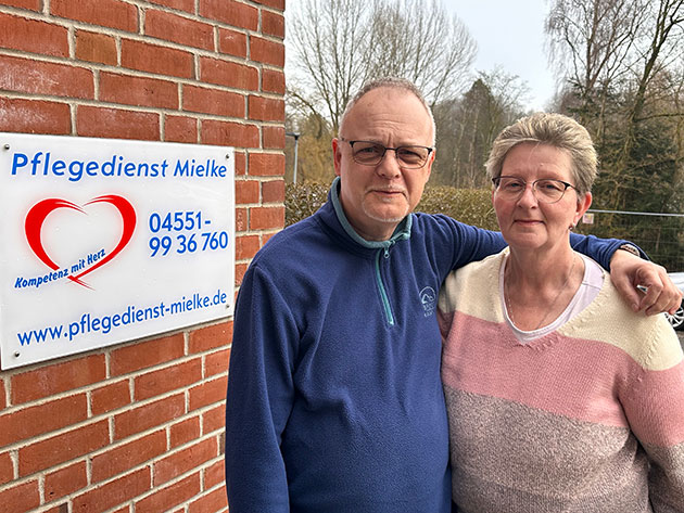 Zwei Personen vor einem Schild des Pflegedienstes Mielke.