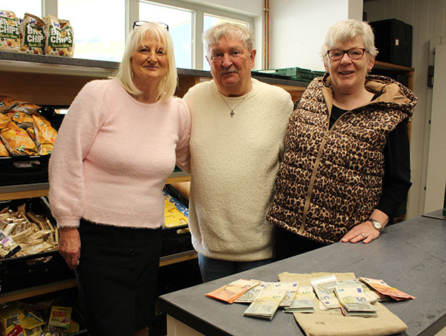 Drei Personen in einem Geschäft zeigen eine Spende von Banknoten.