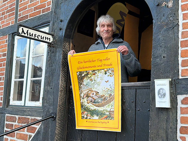 Person hält ein Plakat vor einem Museumseingang.