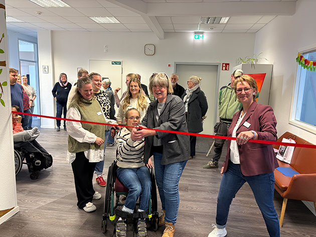 Personen schneiden ein rotes Band in einem Büro durch.