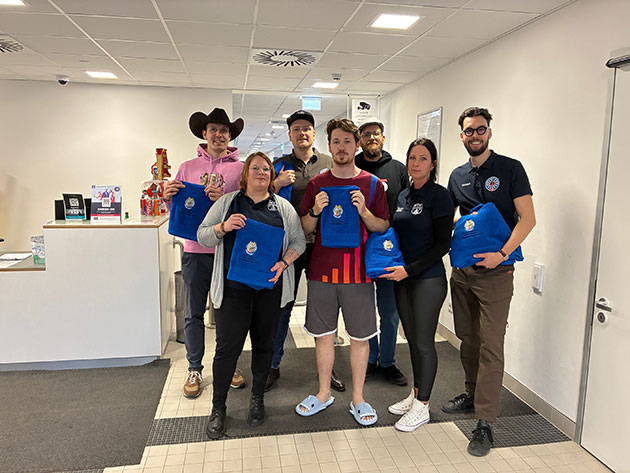 Gruppe von Menschen hält blaue Decken in einem Büro.