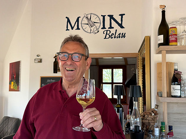 Mann mit Weinglas in einem gemütlichen Raum.