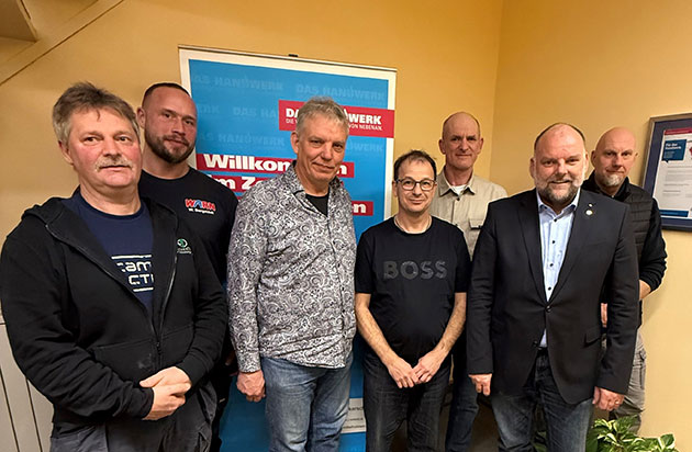 Gruppe von Männern vor einem Banner mit Handwerksschriftzug.