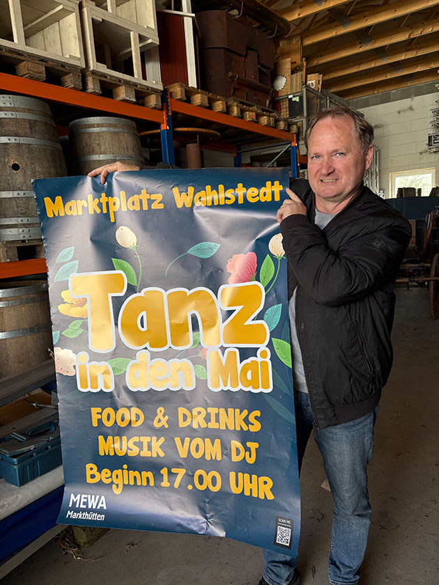 Mann hält Plakat für Tanz in den Mai in Wahlstedt