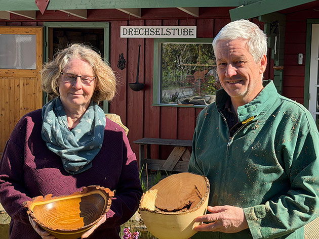 Zwei Personen halten Holzschalen vor der Drechselstube.