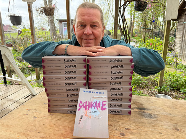 Person lehnt auf einem Tisch mit gestapelten Büchern.