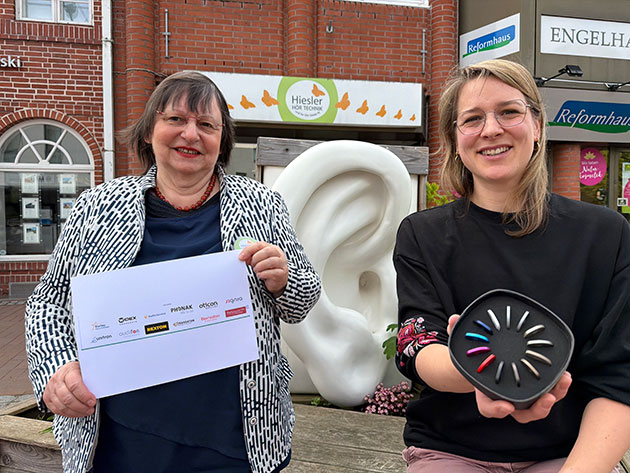 Zwei Frauen vor Skulptur eines überdimensionalen Ohrs in der Stadt.