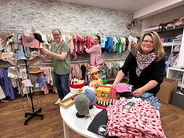 Frauen arrangieren Kleidung in einem Kinderbekleidungsgeschäft.