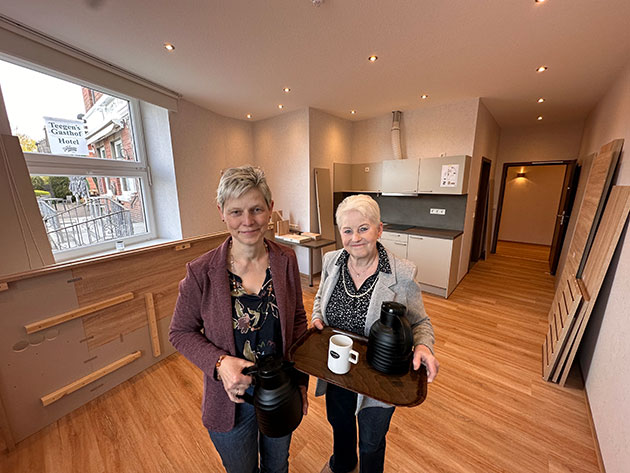 Zwei Frauen mit Tablett im modernen Raum.