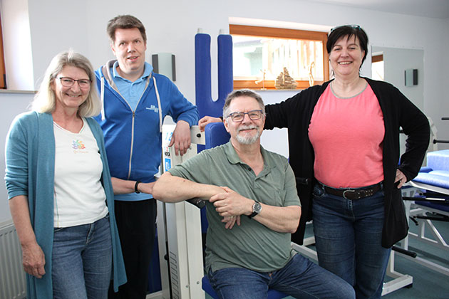 Vier Menschen in einem Fitnessstudio lächeln in die Kamera.