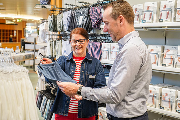 Zwei Personen im Gespräch in einem Bekleidungsgeschäft.