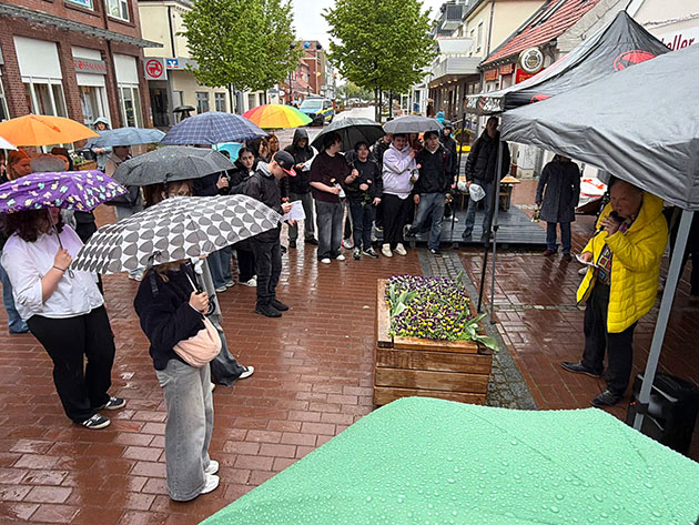 Menschen mit Regenschirmen bei einer Veranstaltung im Freien.