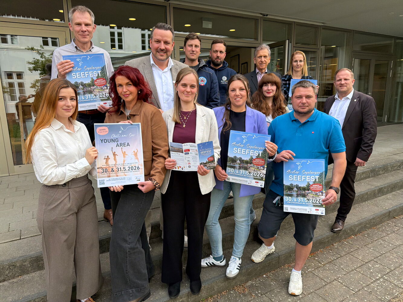 Personen halten Seefest-Poster vor einem Gebäude
