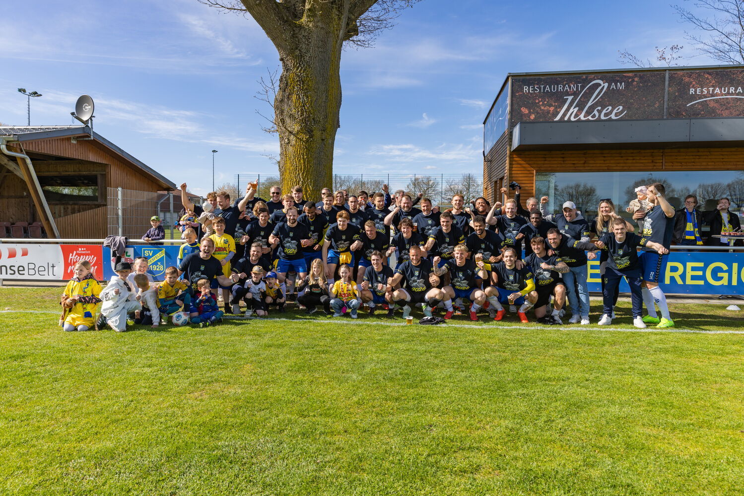 Fußballteam feiert vor einem Restaurant am See.