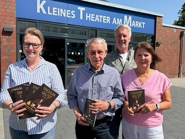 Vier Personen halten Programme vorm Theater.
