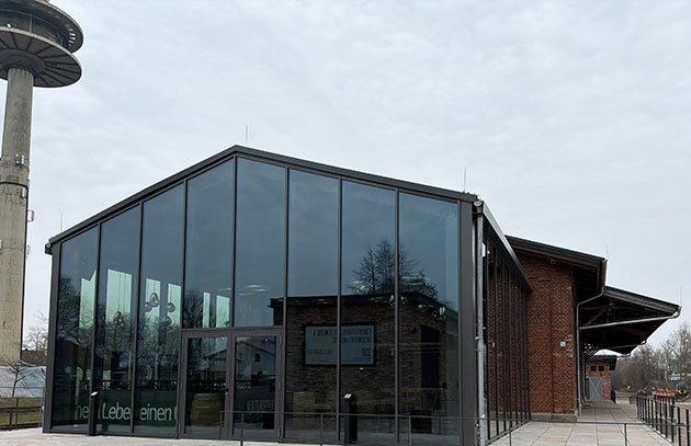 Modernes Glasgebäude neben älterem Backsteingebäude.