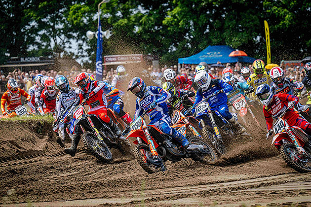 Motocross-Rennen auf sandiger Strecke mit vielen Fahrern.