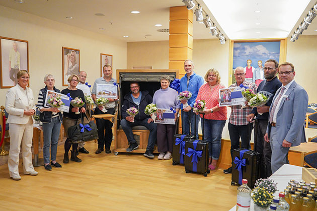 Gruppe von Personen hält Blumensträuße und Urkunden.