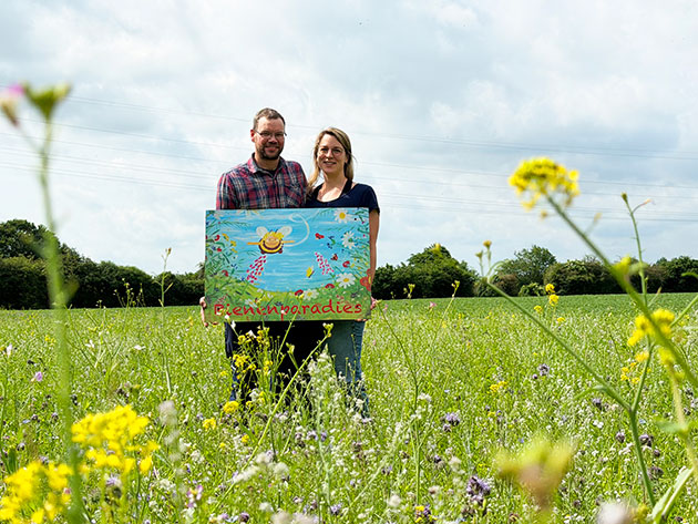 Paar steht auf einer Blumenwiese mit einem Bienenbild.