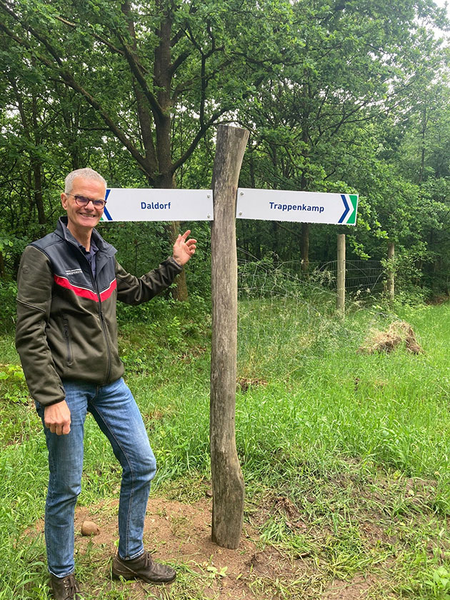 Person neben Wegweiser im Wald zu Daldorf und Trappenkamp.