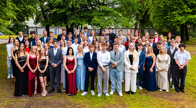 Gruppenfoto von festlich gekleideten jungen Erwachsenen im Freien.