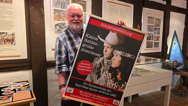 Mann hält ein Plakat zur Karl-May-Ausstellung im Museum.