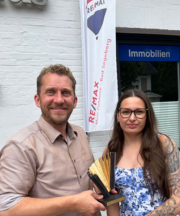Zwei Personen mit einem Preis bei Remax Immobilien.