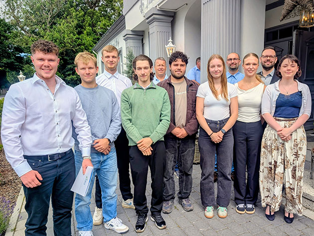 Gruppe von Menschen posiert draußen vor einem Gebäude.