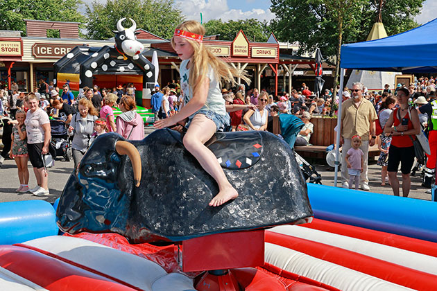 Kind reitet einen mechanischen Bullen auf Jahrmarkt.