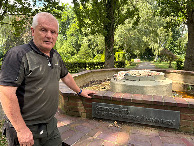 Mann steht vor einem Gedenkstein in einem Park.