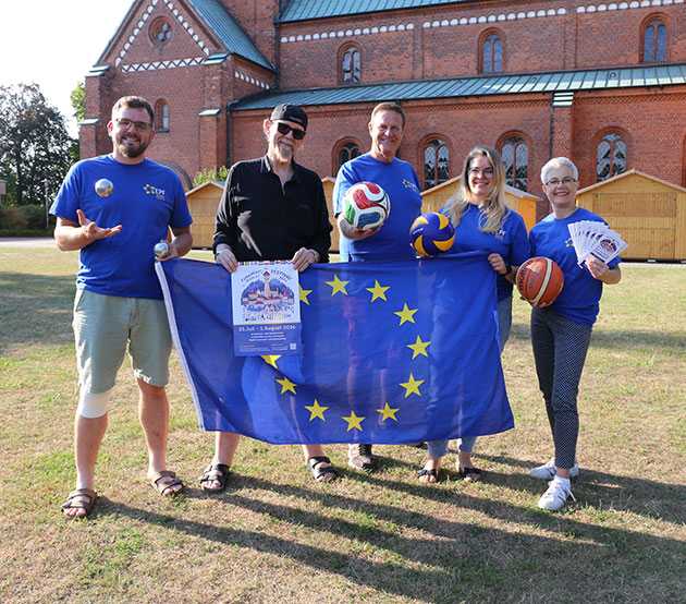 Gruppe vor Kirche mit EU-Flagge und Sportbällen