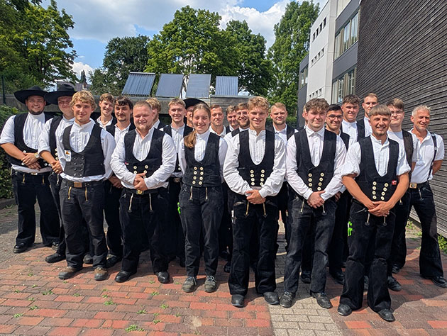 Gruppe von Menschen in traditioneller Arbeitskleidung draußen